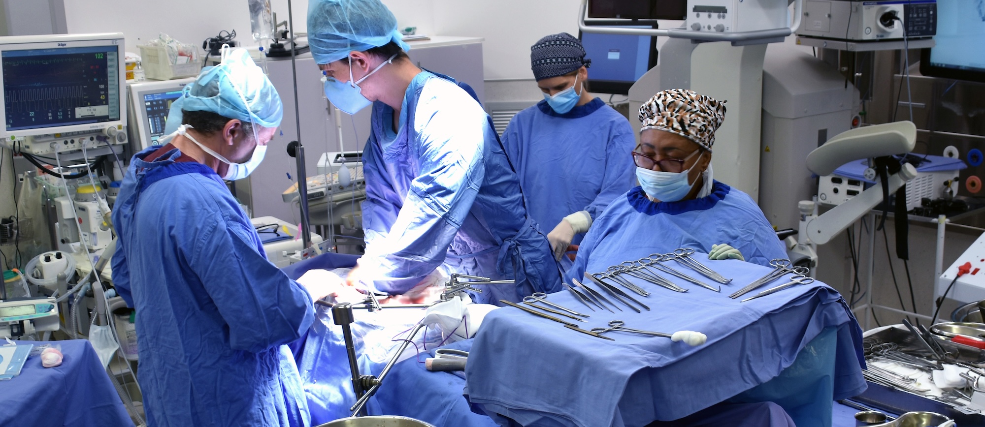Surgical procedure in progress, two JAUC doctors and a scrub nurse are busy with the patient whilst the anaesthetist monitors the vital signs of the patient